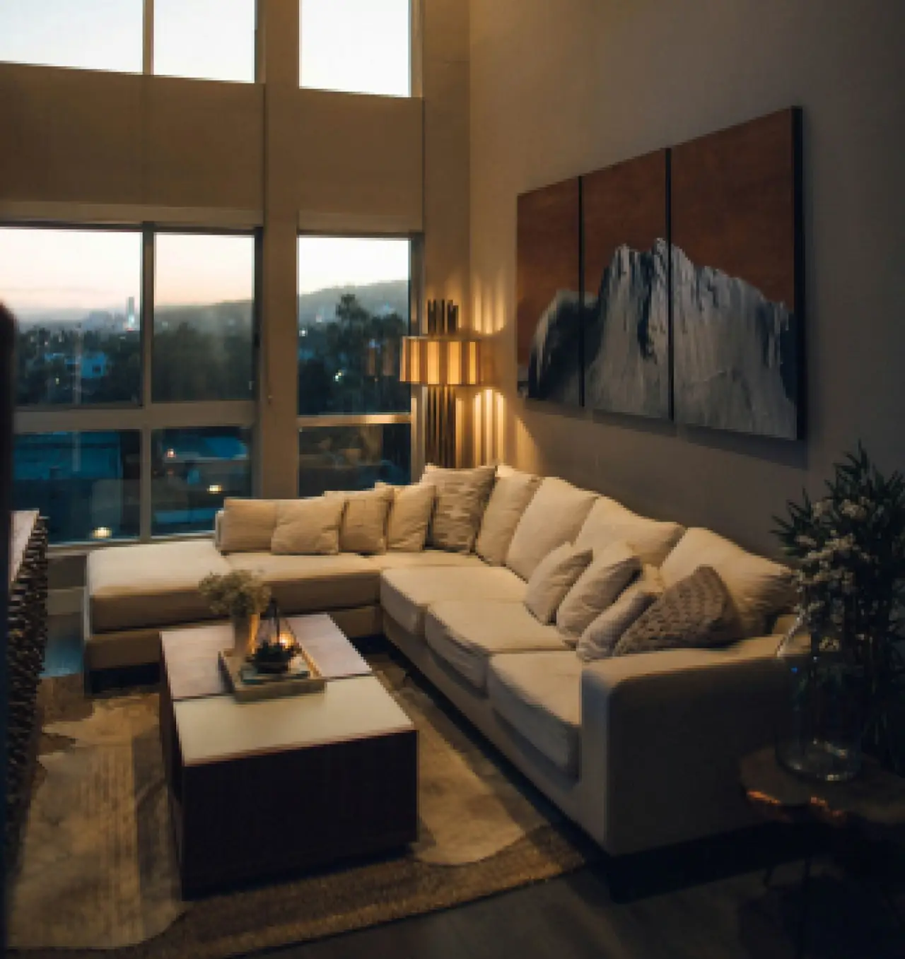 Open plan lounge at dusk with warm lamps and a mountain triptych